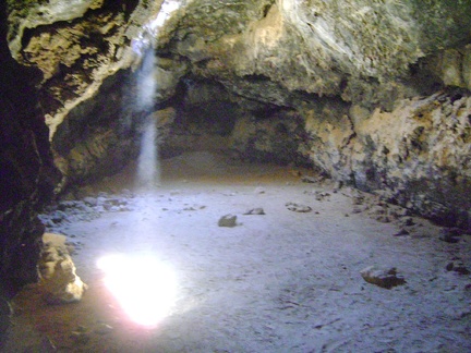 A beam of warm desert light shines down through the ceiling into the main room at the Lava Tube