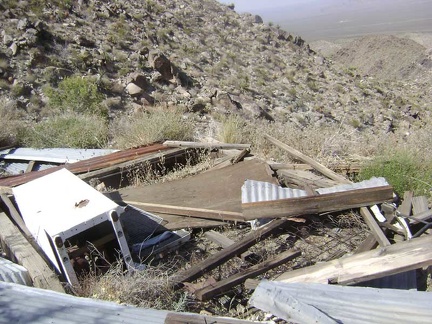 Debris from an old collapsed cabin, including its refrigerator, sits at the top of the road at Bighorn Basin Mine