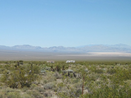 Across the Ivanpah Valley creosote bushes, I see an old trailer and what looks like a garage