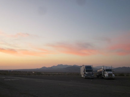 Big rigs park at the Ludlow gas station with the Sleeping Beauty mountains as a sunset backdrop