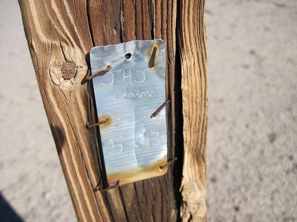 I notice a very weathered old fence post with a metal claim marker as I approach Broadwell Dry Lake