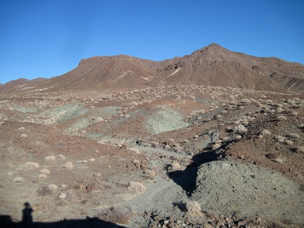 Just beyond the natural arch is Broadwell Mesa and greyish-green minerals coming to the surface everywhere