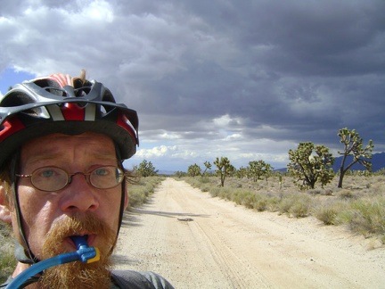 I pop out from under the dark clouds to bright sunshine and a smoother part of Aiken Mine Road, so I'm back on the bike