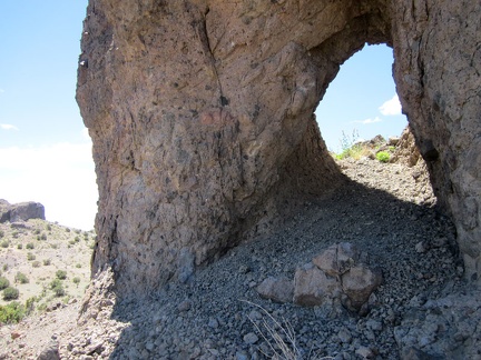 I crouch and walk through this little rock arch in the Castle Peaks area