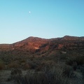 A close-to-full moon sits above the Woods Mountains just before sunset on this hot day