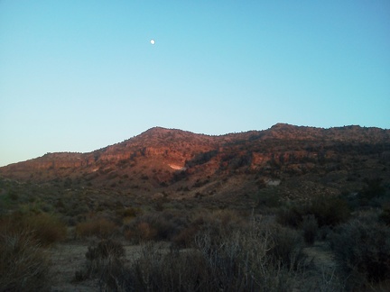 A close-to-full moon sits above the Woods Mountains just before sunset on this hot day