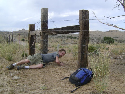 I crawl under a barbed-wire fence so I can walk up Wild Horse Canyon Road