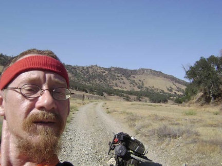 Before I remount the 10-ton bike and turn back, I snap a shot of us with the Rooster Comb in the background.