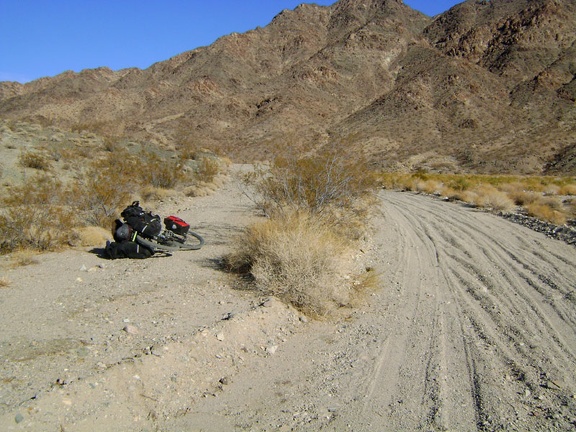 I try riding the worn-out paved track along the wash to avoid the deep sand and gravel in Jackass Canyon