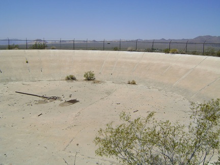 Peering through the wire, I see a large, dry concrete reservoir