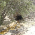 A trickle of rusty, contaminated water exudes from a tunnel in the hillside above the mine tailings