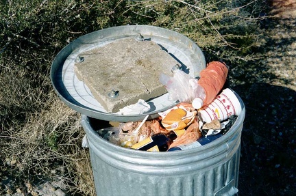 Concrete attached to the inside of a garbage can lid at the campground