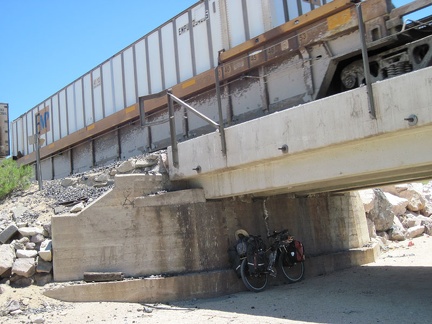 The 10-ton bike hides in the shade of the trestle at Joshua siding while a freight train rumbles overhead