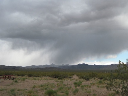 Beyond the Nipton campground, I see storm clouds over the Castle Peaks, those pointy distant mountains