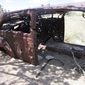 Not only is the old car (1940s?) well-shot-up, but it's well-buried in sand