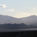 Vehicles on the I-15 freeway, on the other side of Ivanpah Valley, glisten as the setting sun peers through the clouds