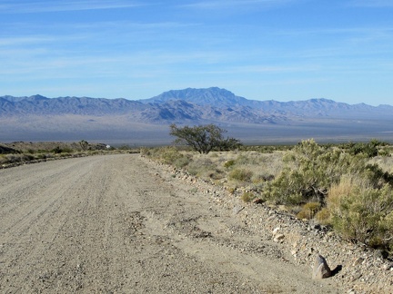 Back on the 10-ton bike, riding down the dirt of Ivanpah Road, the pavement starts by that sign just ahead
