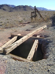 Along the trackway is an open shaft and the main headframe, with the Providence Mountains in the background