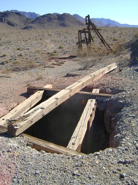 Along the trackway is an open shaft and the main headframe, with the Providence Mountains in the background