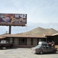 A billboard next to the Searchlight motel advertises a "luxury" motel elsewhere