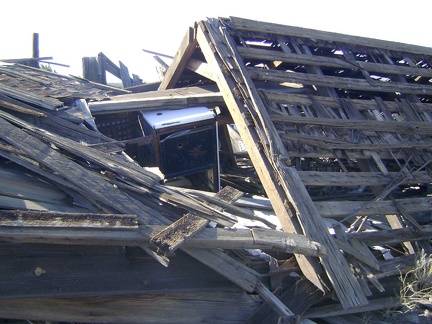 An old stove is crushed beneath the collapsed roof of this house at Cima, Mojave National Preserve