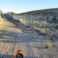 The road narrows and I find myself riding along a chain-link fence