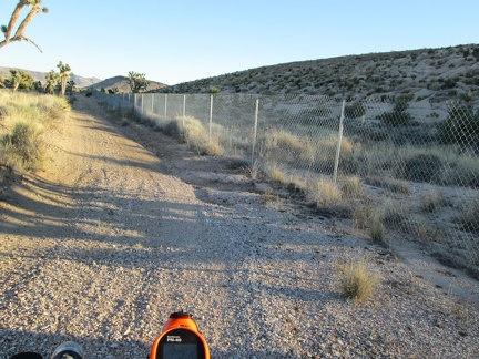 The road narrows and I find myself riding along a chain-link fence