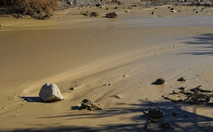 A rock slowly slides downstream in a river of mud after a day of heavy rain, Death Valley National Park